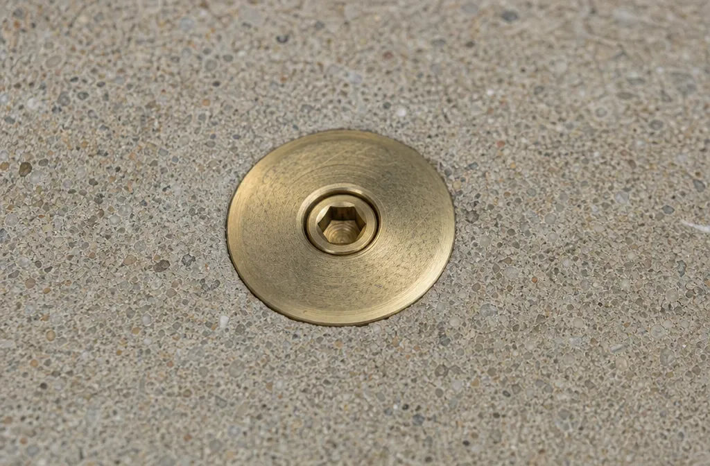 A brass deck anchor set flush in a pool deck
