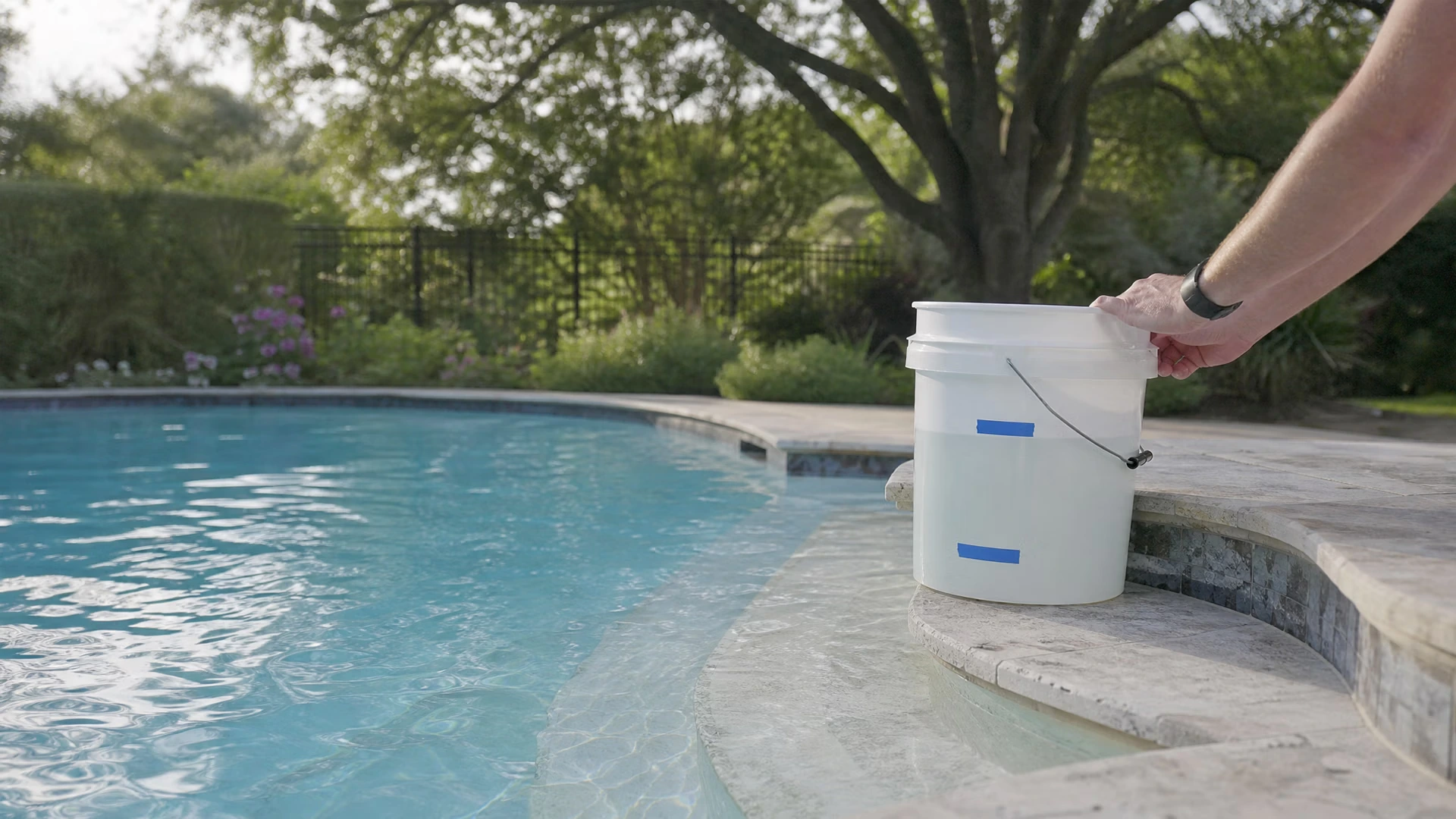 A bucket standing on the top step of an in-ground pool with its inside and outside water levels marked in tape