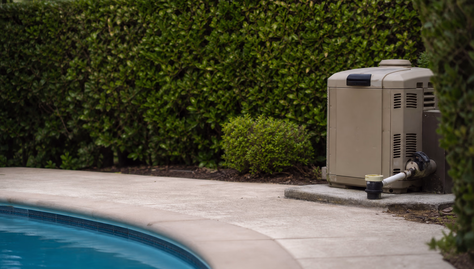 An old pool heater disconnected and capped on its pad