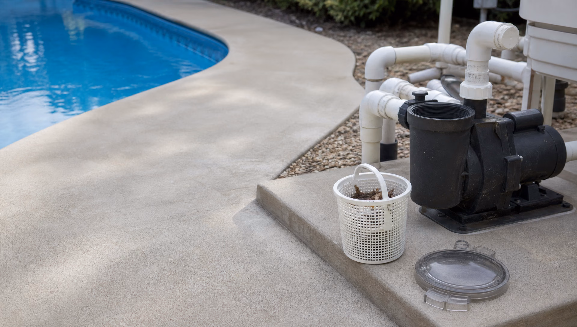 A pool pump with its strainer lid off and the basket lifted out