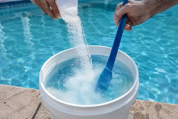 Granular pool sanitiser being pre-dissolved in a bucket