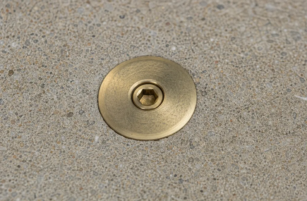 A brass deck anchor set flush in a pool deck