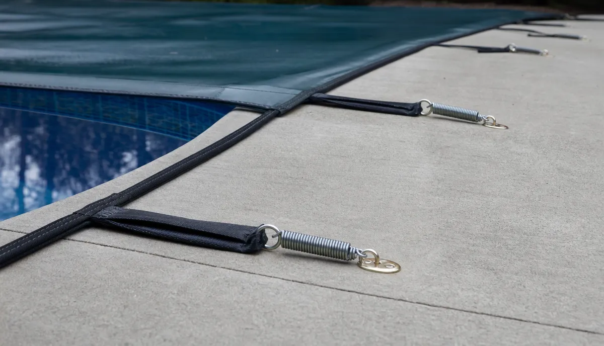 Spring-tensioned straps running from a cover to its anchors